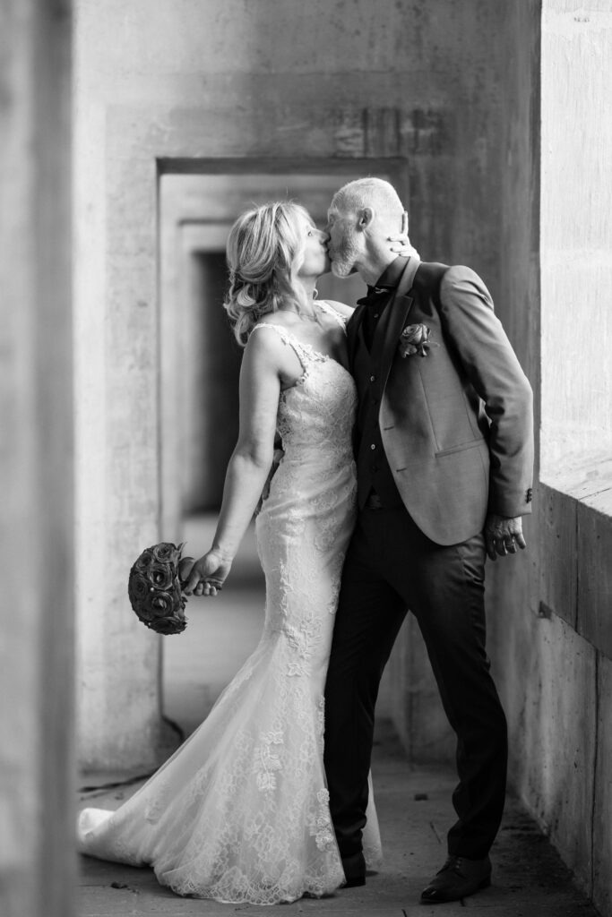 Couple mariés s'embrassant, style photographie noir et blanc.